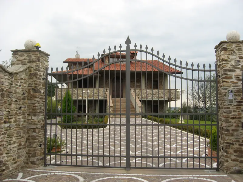 Cancello automatico a due ante con lampeggiante sul pilastro in pietra, ingresso di una villa
