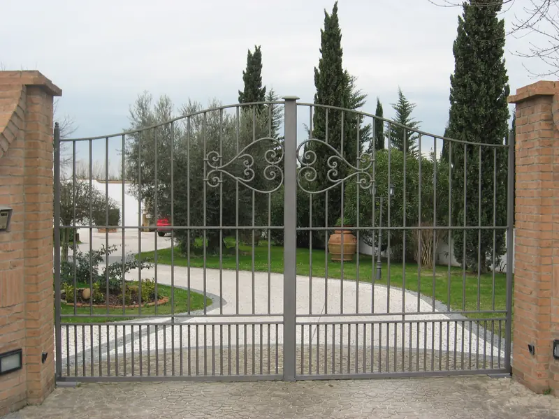 Cancello a battente automatico all’ingresso di una villa con cipressi